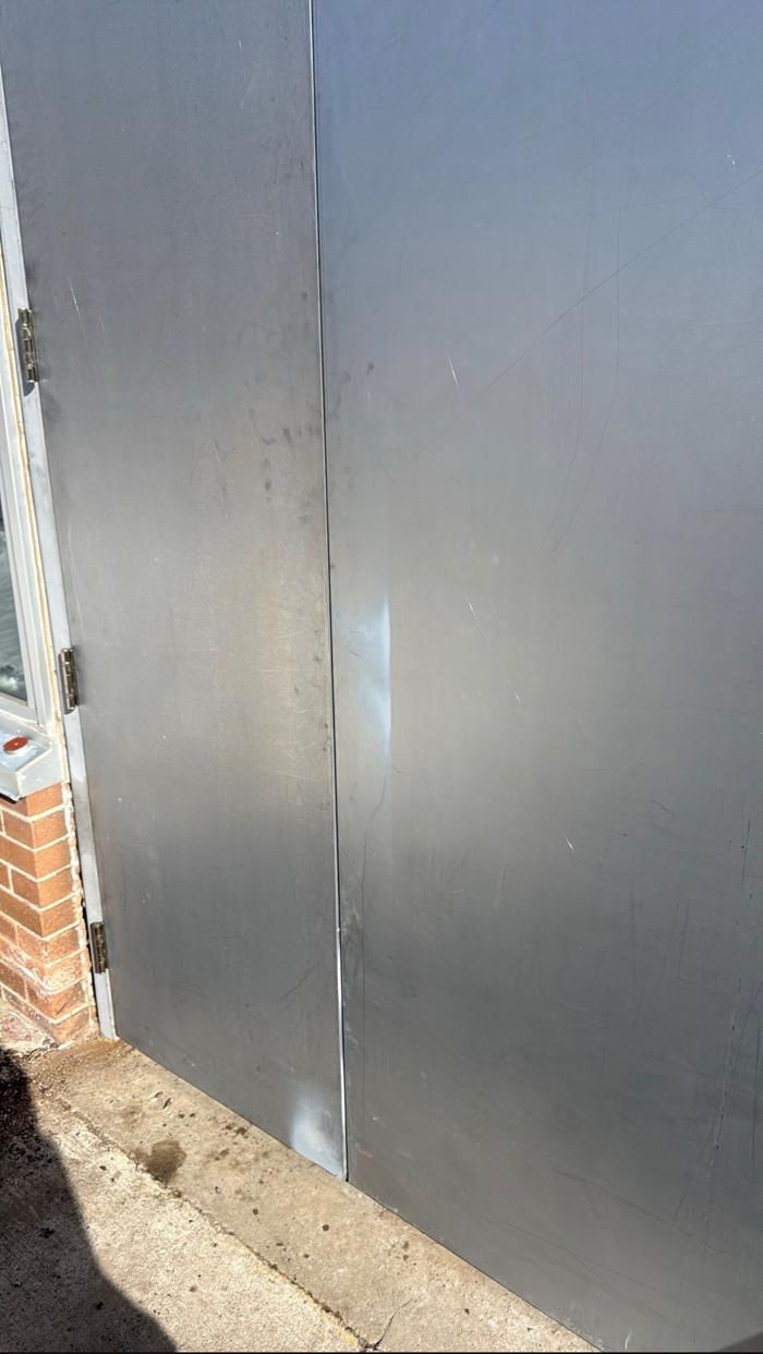 After: new commercial hollow steel double doors at an Ottawa school, exterior view with a clean primer-grey finish ready for paint