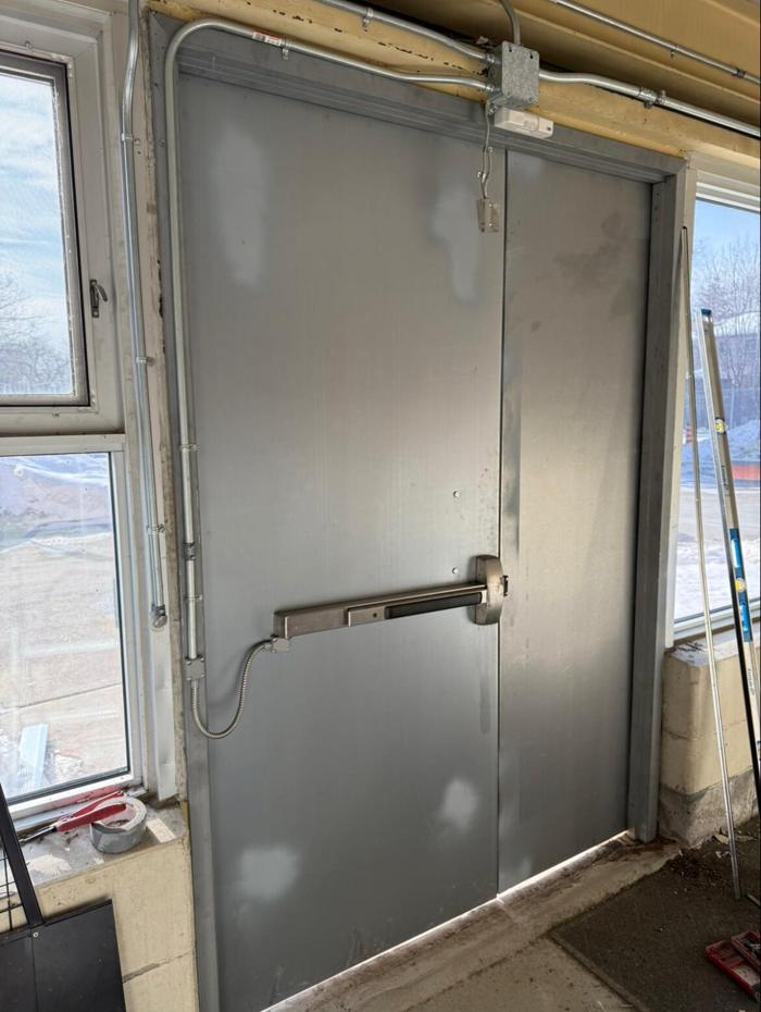 After: interior view of the new school doors with the electrified panic bar wired to the fire alarm, new closers and fire alarm contacts