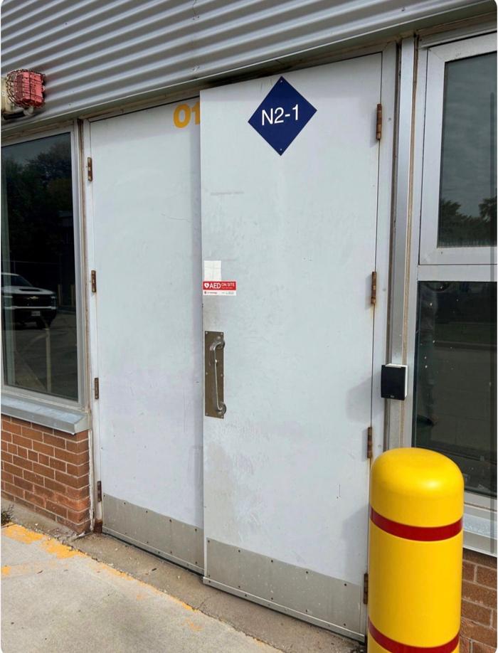 Before: worn commercial hollow steel double doors at an Ottawa school, exterior view showing corrosion and a faded finish