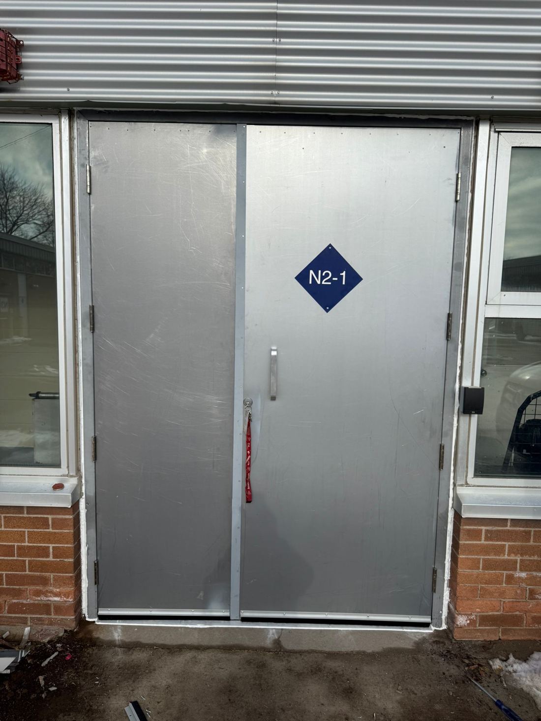 Architectural fire-rated steel double door with a blue fire-compartment zone marker installed in a hollow-metal frame at an Ottawa building