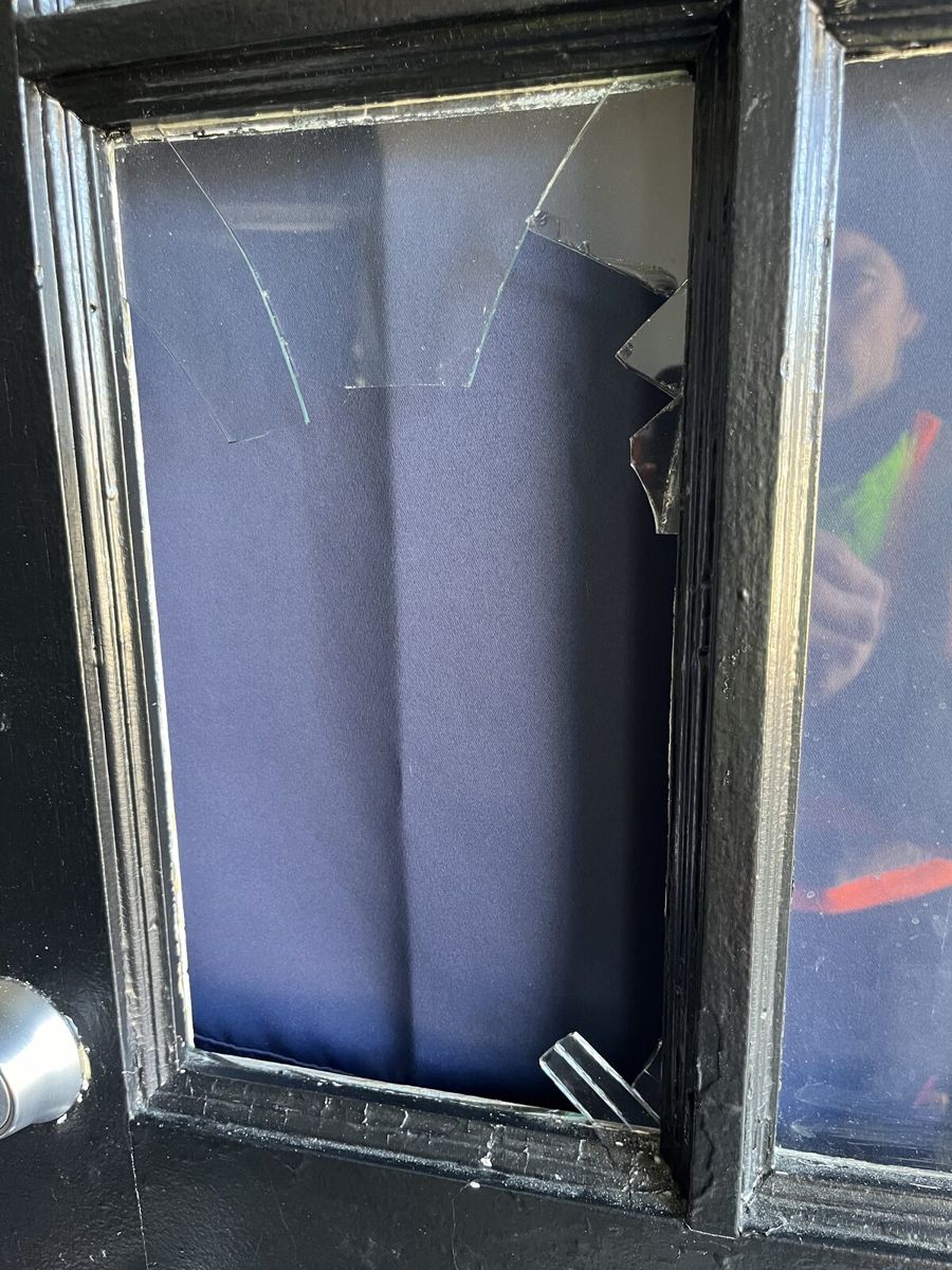 Smashed glass pane in a black entry door at an Ottawa home before repair
