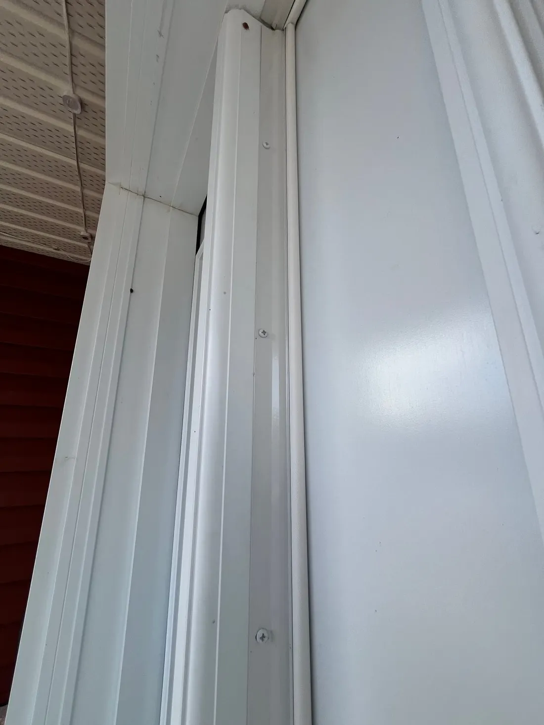 White metal jamb reinforcement screwed along an exterior door frame up to the head jamb