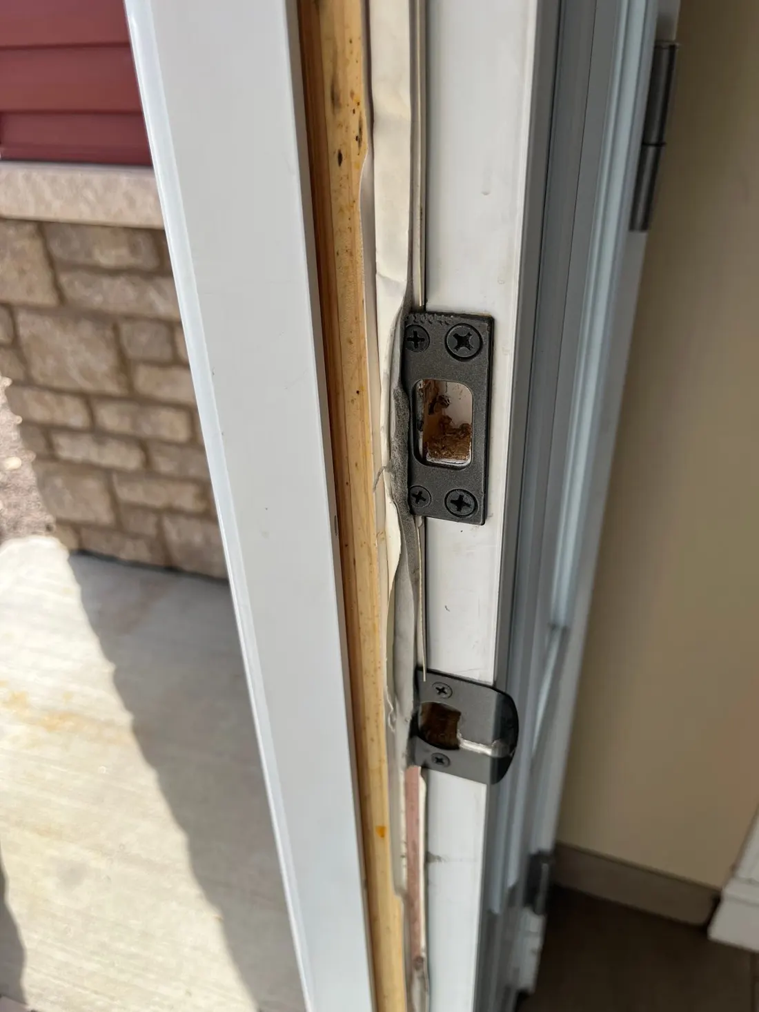 Exterior door jamb split along the strike side, exposing bare wood behind the deadbolt and latch strike plates