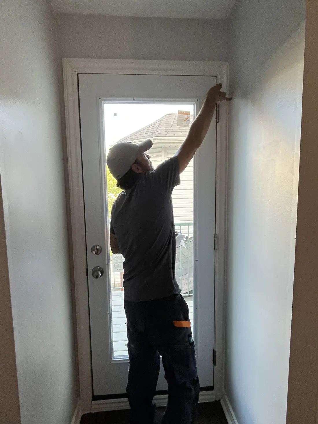 Technician adjusting the hinge on a newly installed white exterior replacement door