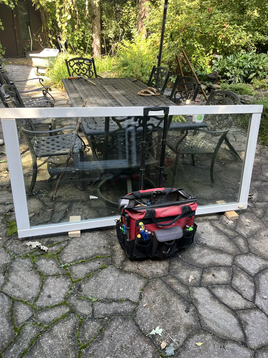 Patio door panel removed for roller replacement in Gatineau, with tool bag on the patio