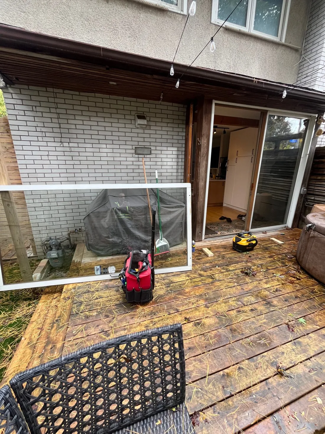 Operable sliding patio door panel removed and leaning on a deck in Westboro during roller replacement, with the open door frame behind it