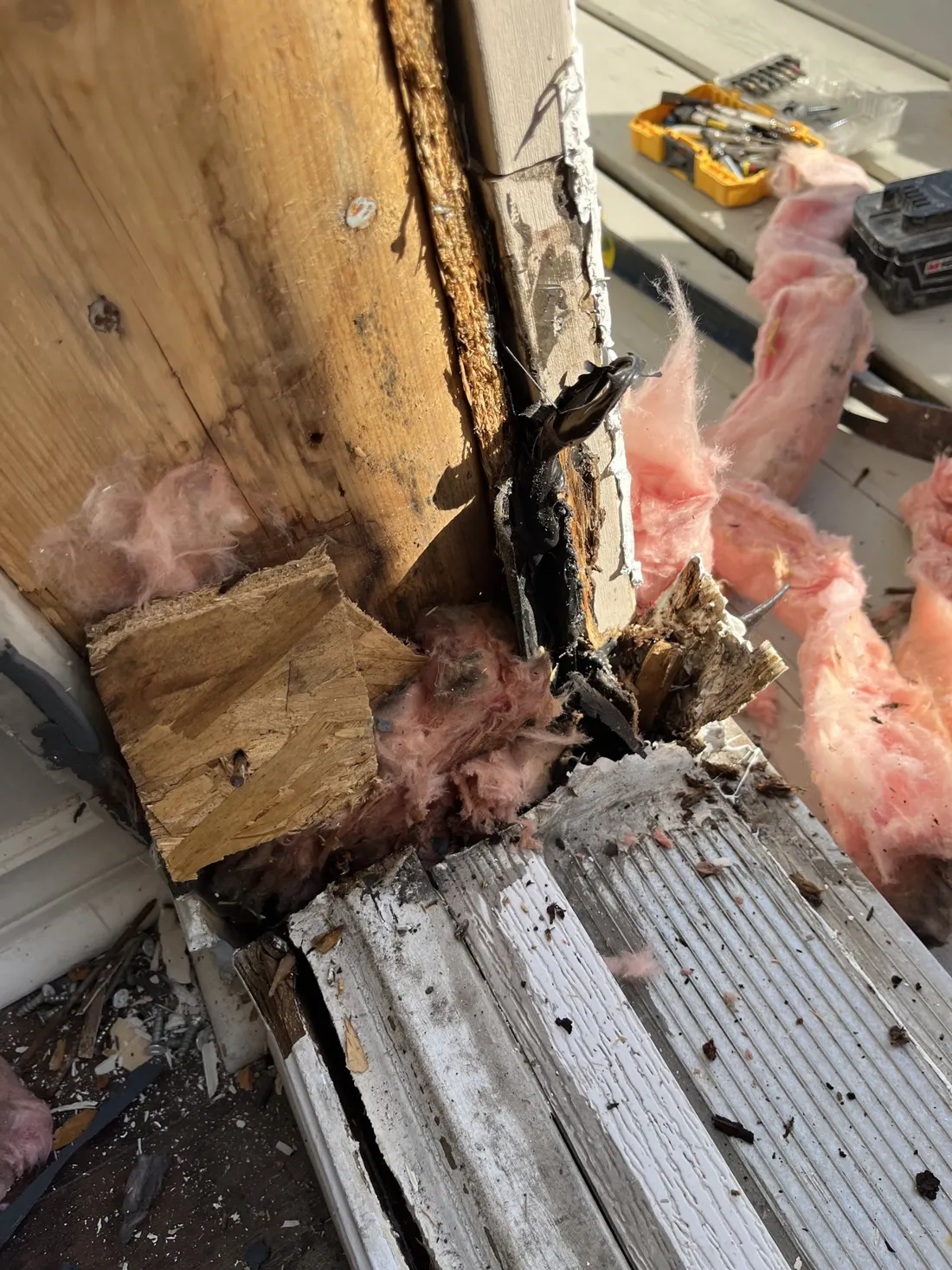 Severe water-damaged and rotted wood at the bottom corner of an exterior door jamb