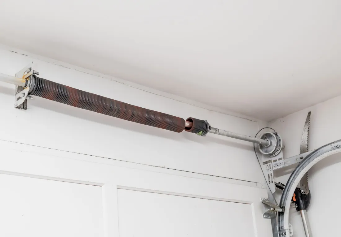 Garage door extension spring, pulley and lift cable mounted along the ceiling