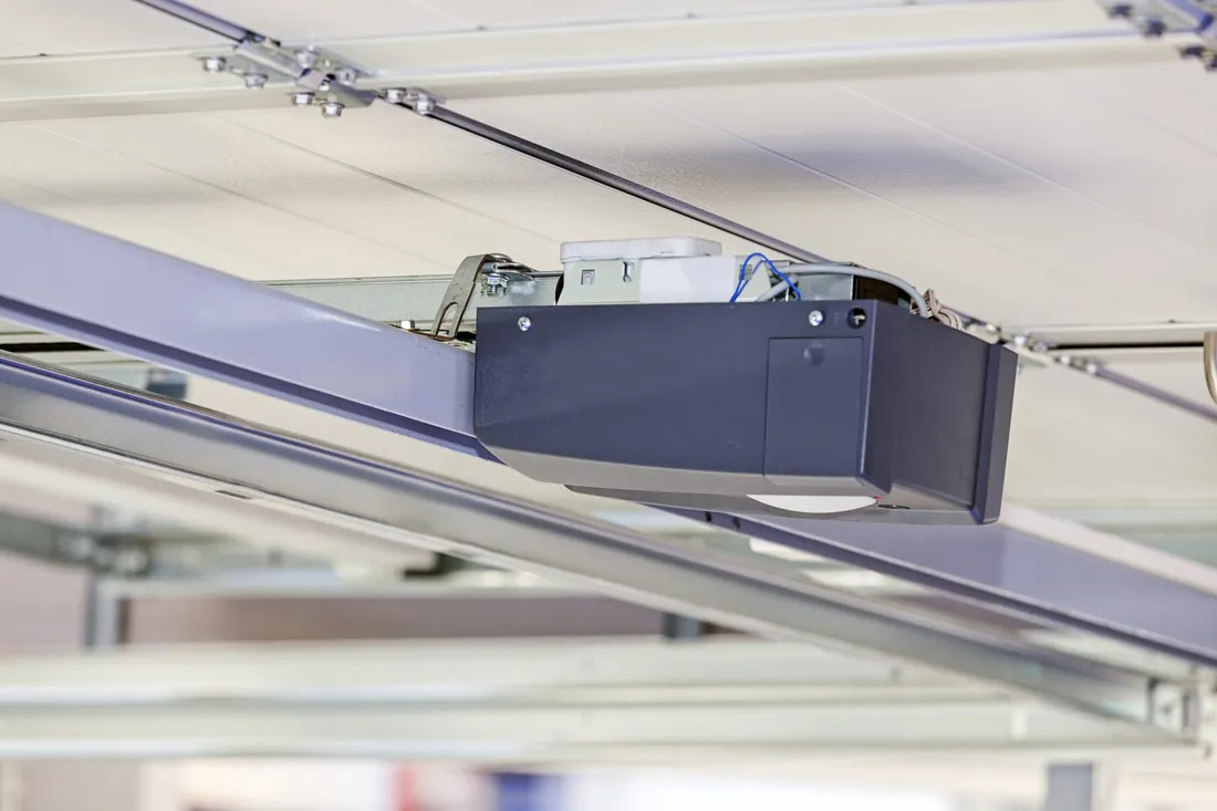 Garage door opener motor unit mounted on its ceiling rail above the door panels