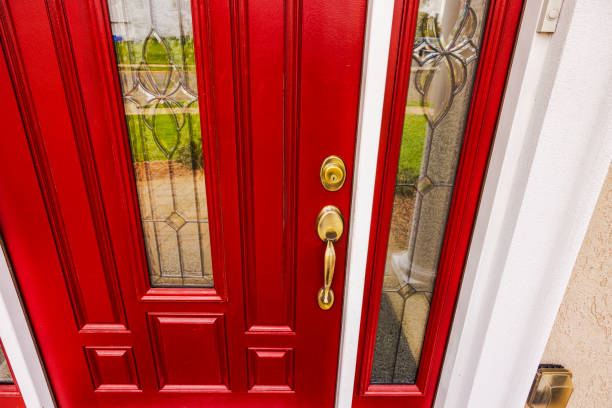 Red panelled entry door with a brass handleset and deadbolt, leaded glass lite and a matching leaded sidelite