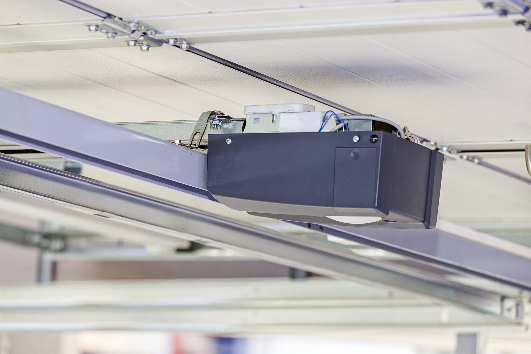 Garage door opener motor unit mounted on the ceiling rail above a sectional door