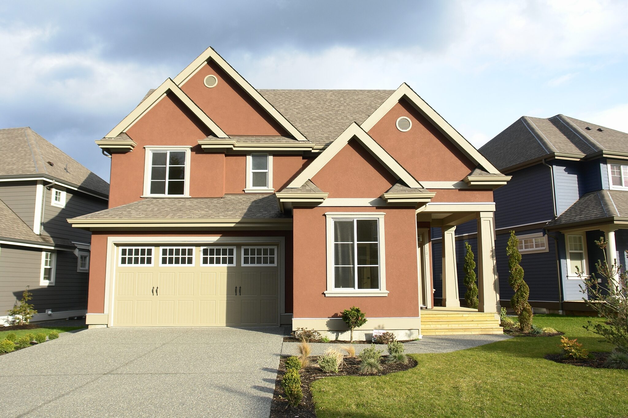 Beige double-width garage door with a row of windows on a two-storey suburban home